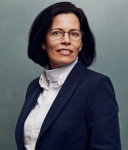 Meet the Team of experts - Photo of Caroline Verheyden, person in business suit, glasses with dark frames, smiling, female, friendly, standing upright