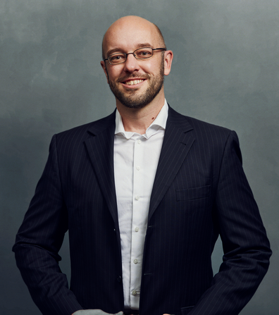 Meet the Team of experts - Photo of Carsten Krüger, person in business suit, glasses with dark frames, smiling, male, gallantly, standing upright